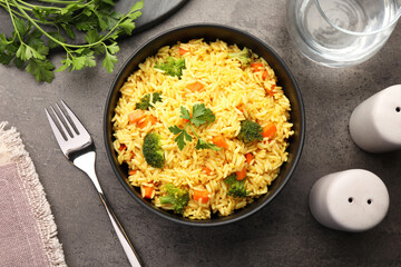 Tasty rice with vegetables served on grey table, top view