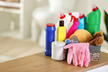 Different cleaning supplies on wooden nightstand in bathroom, space for text