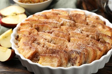 Delicious bread pudding with raisins, cinnamon and apples on wooden table, closeup