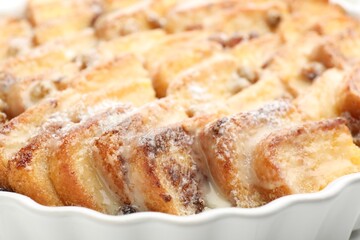 Delicious bread pudding with raisins and powdered sugar in dish, closeup