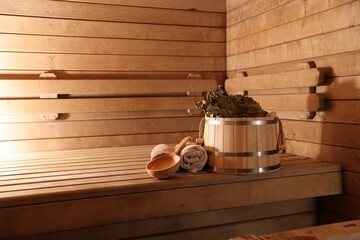 Bucket, whisk, ladle and towels on wooden bench in sauna. Space for text