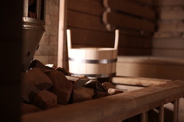 Stove with hot rocks and bucket in sauna