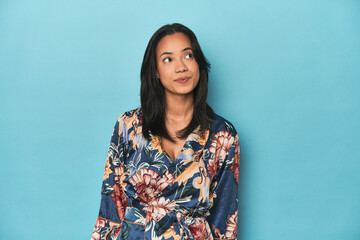 Filipina in floral kimono on blue studio dreaming of achieving goals and purposes