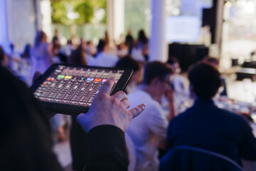 View of lighting technician with tablet, operator controlling sound and light during live event...