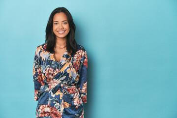 Joyful Filipina in traditional kimono posing on blue studio backdrop