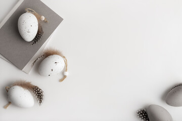 Decorative eggs in natural colours with a notepad on the white table. Flat lay, top view, happy easter concept.
