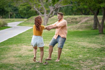 Fototapeta premium Playful couple spinning around in a park