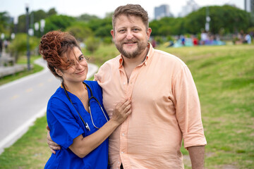 Obraz premium Female doctor with her boyfriend in a park looking smiling at the camera