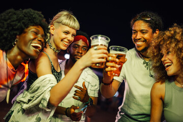 Happy friends toasting with beer glasses at music festival
