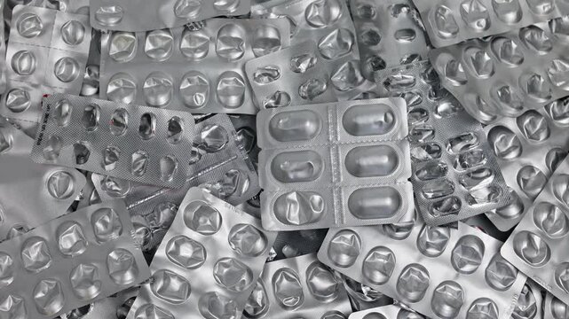 Closeup shot of falling pill blister on top of pile of empty pill blister packs. Treatment and medication concept