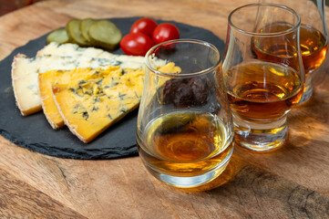 Whiskey and cheese pairing, tasting whisky glasses and plate with sliced crumbly old blue stilton...