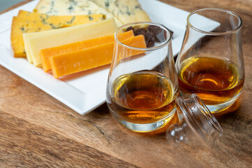 Whiskey and cheese pairing, tasting speyside whisky glasses and plate with sliced cheddar, blue stilton and blue shropshire cheeses, Great Britain food and drink