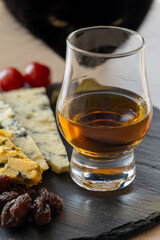 Whiskey and cheese pairing, tasting whisky glass and plate with sliced blue stilton and blue shropshire cheeses, Great Britain food and drink