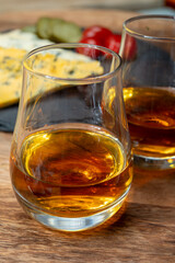 Whiskey and cheese pairing, tasting whisky glasses and plate with sliced crumbly old blue stilton and blue shropshire cheeses, Great Britain food and drink