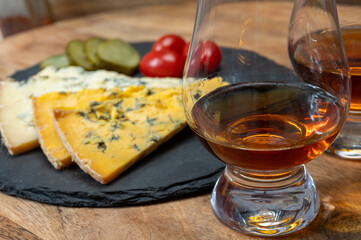 Whiskey and cheese pairing, tasting whisky glasses and plate with sliced crumbly old blue stilton and blue shropshire cheeses, Great Britain food and drink