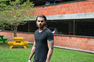 Young tattooed man portrait in a park outdoors