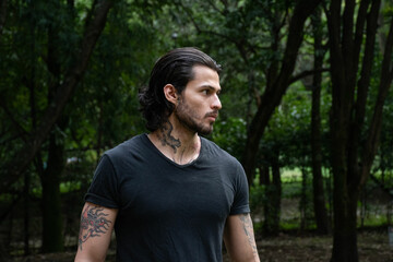 Young tattooed man portrait in a park outdoors