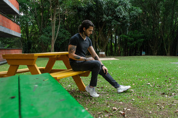 Young man sitting on a bench in a park outdoors