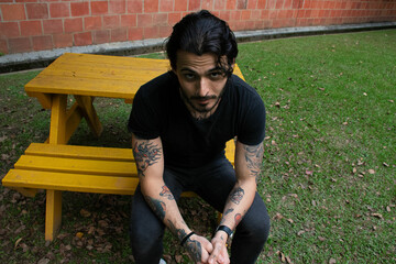 Young man sitting on a bench in a park outdoors