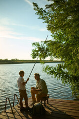 Grandfather and grandson sharing a special moment fishing on a wooden dock
