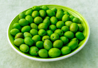 Beautiful kitchen plate with fresh green olives on monochrome green salad background. Olive dish closeup, foor and drink concept