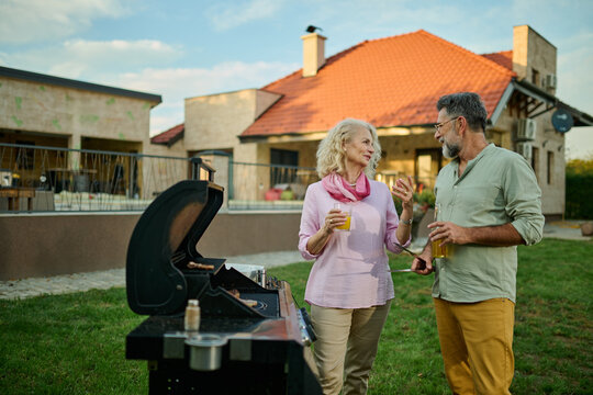 Senior couple enjoying barbecue party on backyard of their home