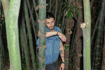 Young tattooed man portrait surrounded by nature outdoors.