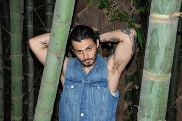 Young tattooed man portrait surrounded by nature outdoors.