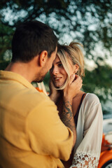 Fototapeta premium Romantic couple embracing by the lake at sunset