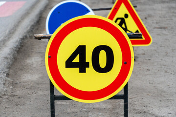 Multiple road signs display a 40 km/h speed limit alongside construction warnings, directing traffic in an urban setting