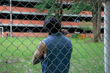 Young tattooed man standing next to a soccer goal in a park surrounded by nature