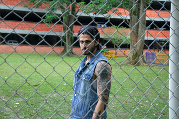 Young tattooed man standing next to a soccer goal in a park surrounded by nature