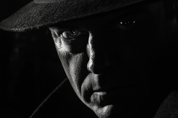 A detective stares intently, his face partially hidden in shadows. The noir lighting adds depth to his expression, creating a mysterious atmosphere typical of a late-night investigation