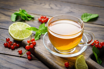 Cup of tea on table red berries green leaves light color