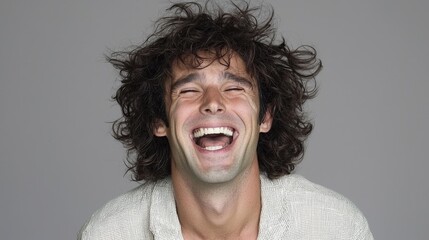 Man laughing broadly against gray background. Possible use stock photo for happiness, humor, or human emotion