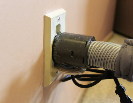 close-up of a residential central vacuum hose wall hook up to the wall plate for cleaning. macro photography graphic element.