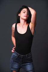 Model poses confidently in a black outfit against a dark backdrop during a studio shoot
