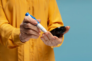 Senior woman checking blood sugar level using lancet pen and glucometer