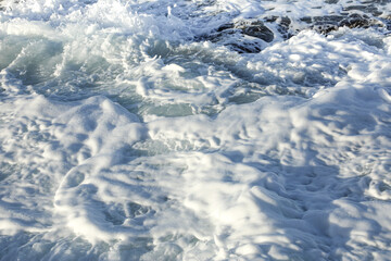 Sea foam close-up in a stormy sea on a sunny day. The structure of the water of the raging sea is...