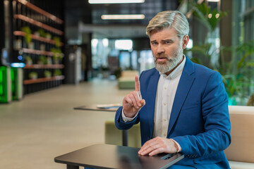 Portrait of mature businessman shakes finger and saying No be careful scolding and giving advice to...