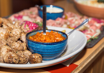 Delicious meatball and tomato dip platter with unique blue bowl on wooden table