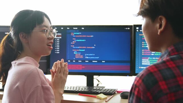 Slow motion back end software developer engineer for computer programming working together on debugging writing computing code, solving complex algorithms display on monitor in office. Burgeoning