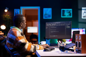 Black software engineer writes complex binary code scripts on computer, cybersecurity. Teleworking IT specialist in home office using programming language to safeguard consumer data.