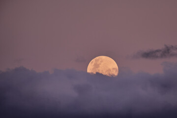 Full Moon Rising Behind Clouds at Dusk