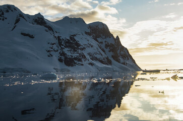 Antarctic Peninsula: Snowy peaks, icebergs, cloudy sky. Lemaire Channel