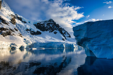 Antarctic Peninsula: Snowy peaks, icebergs, cloudy sky. Lemaire Channel