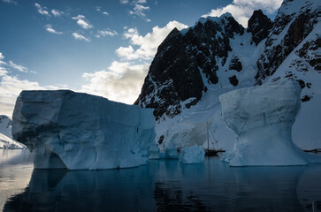 Antarctic Peninsula: Snowy peaks, icebergs, cloudy sky. Lemaire Channel