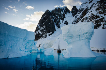Antarctic Peninsula: Snowy peaks, icebergs, cloudy sky. Lemaire Channel