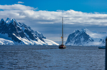 Antarctic Peninsula: Snowy peaks, icebergs, cloudy sky. Lemaire Channel