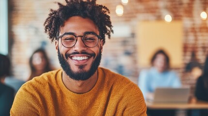 Obraz premium Smiling young Black man wearing glasses and a mustard-colored sweater.